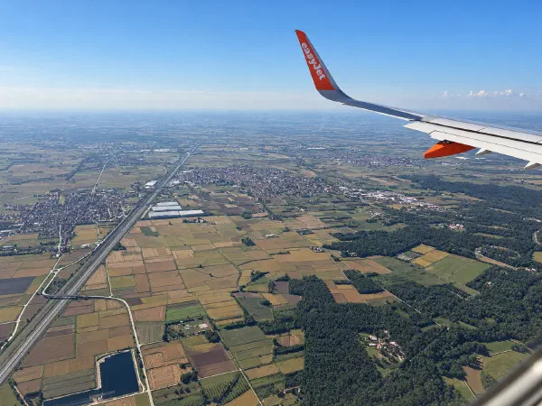 Aerial view of Galliate, its fields and roads, with an aircraft wing above the town.