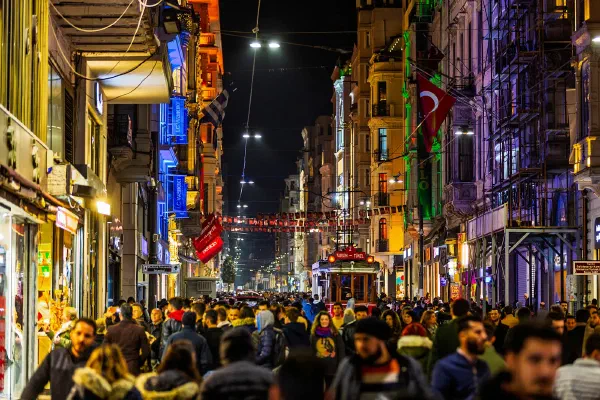 A crowded narrow street glowing with coloured lights at night.
