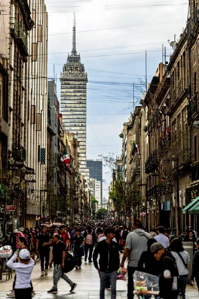 A crowded street running towards a clock tower.
