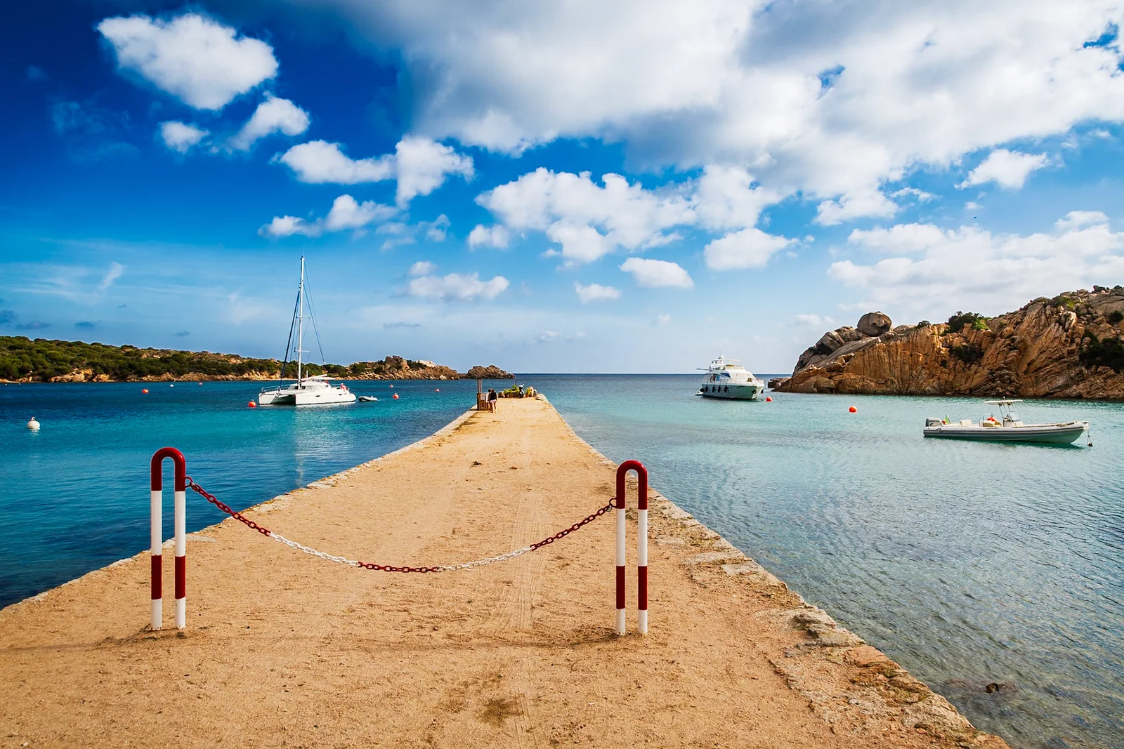 A concrete harbour pier reaching into clear blue water.