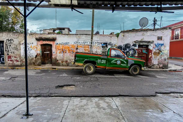 A brightly painted vehicle beside a weathered street building.