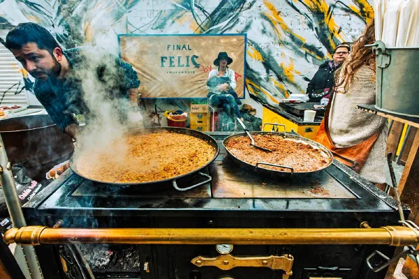 A street cook tending steaming pans of food.