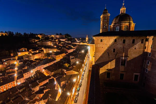 A church and hillside town illuminated against a dark blue night sky.