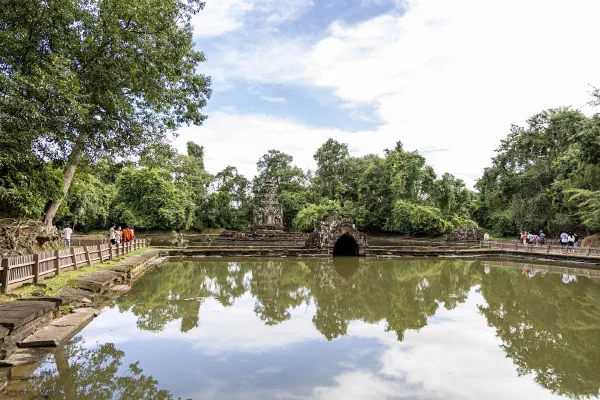 A temple pond reflecting trees and a small stone structure.