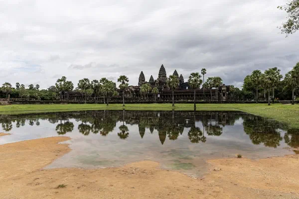 Angkor Wat reflected in a pool beneath a cloudy sky.