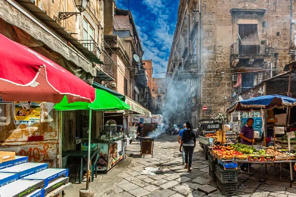 A smoky street market between weathered city buildings.