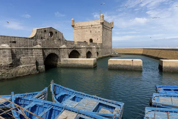 Blue wooden boats below stone harbour fortifications.