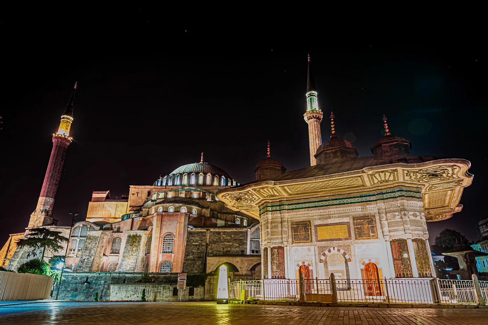An illuminated building with minarets beneath a dark night sky.