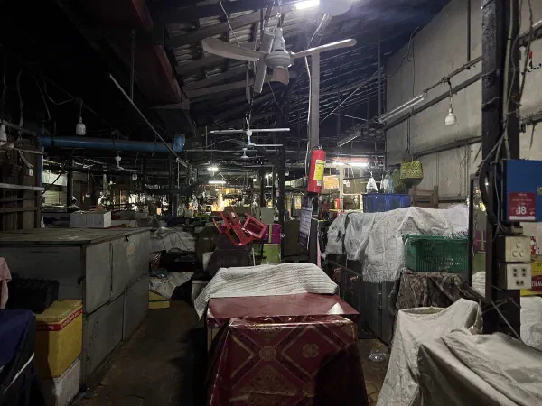 Covered stalls and empty aisles in a market after closing.