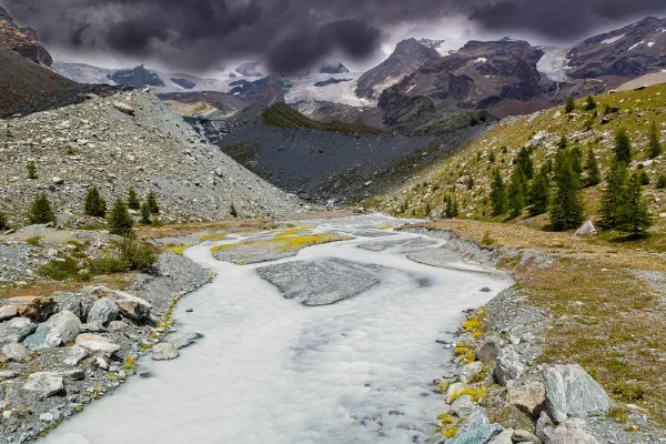 A pale mountain stream winding through a rocky valley.