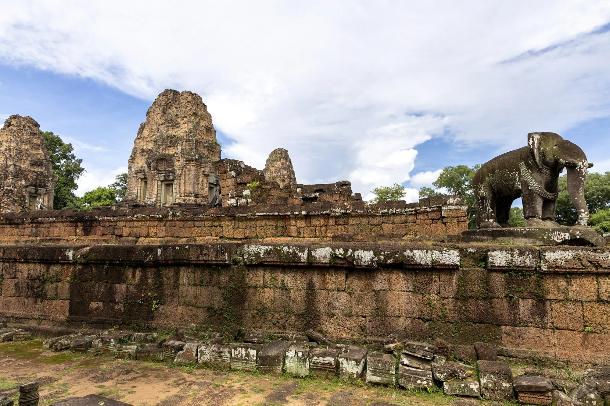 An elephant sculpture and brick temple towers beneath a blue sky.