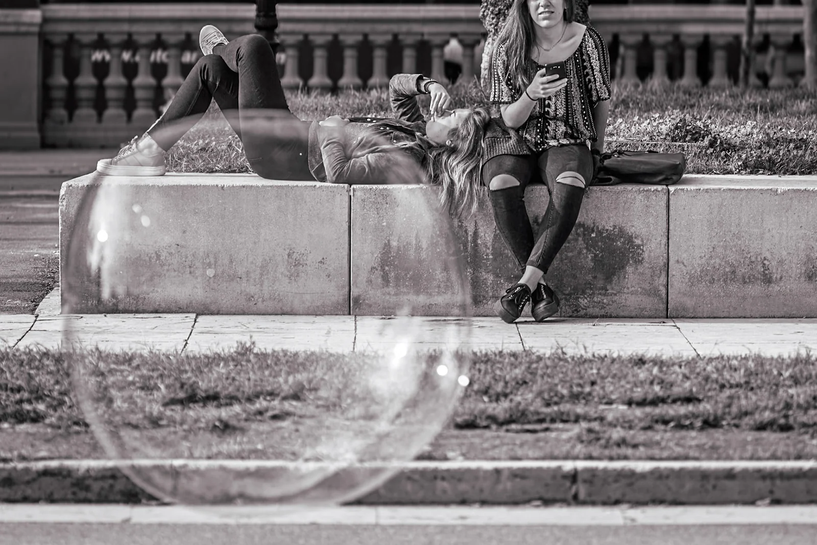 A large soap bubble floating in front of people on stone steps.