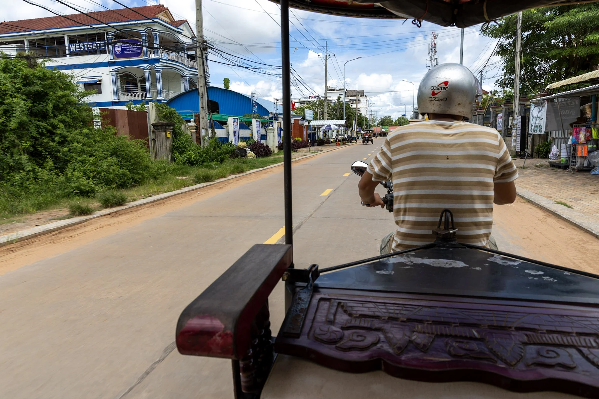 The view from a tuk-tuk behind its driver on a street in Siem Reap.