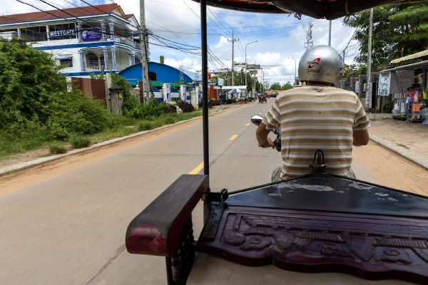 The view from a tuk-tuk behind its driver on a street in Siem Reap.