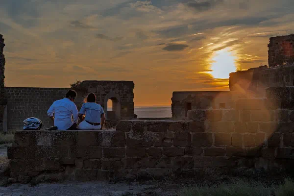 People sitting on a stone wall in warm sunset light.