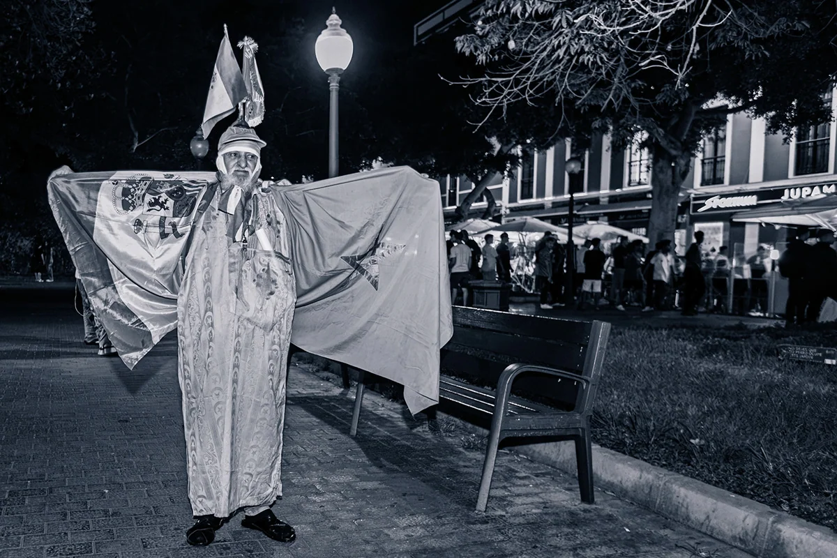 A supporter wearing a flag in a black and white night photograph.